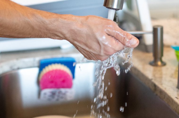 Une personne fait couleur de l'eau du robinet avec sa main en-dessous